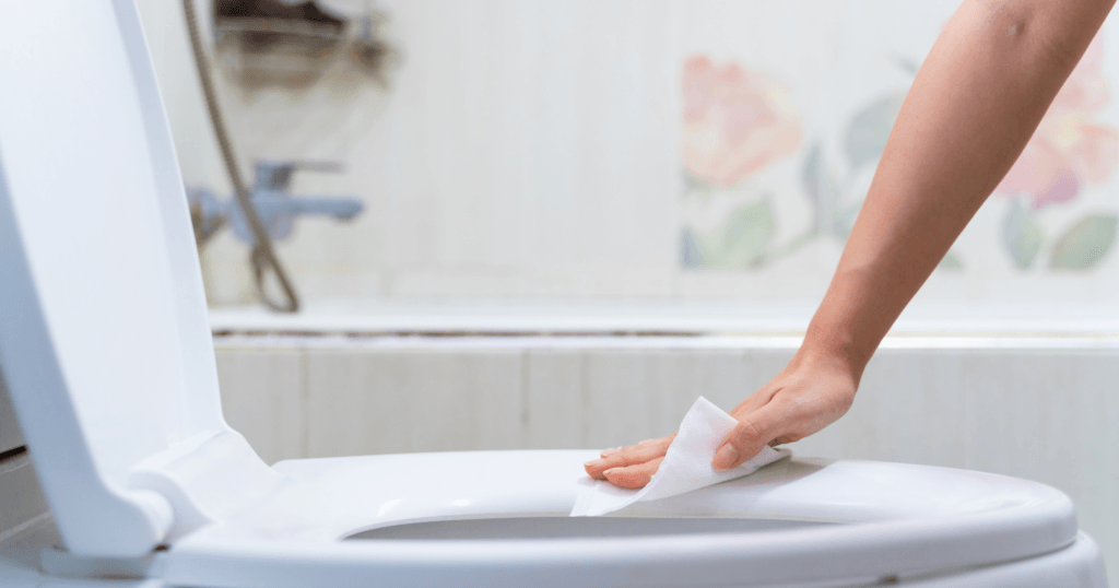 The Best Toilet Seat Surface for Cleaning- hands cleaning a toilet seat