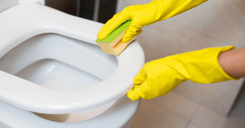 The Best Toilet Seat Surface for Cleaning- hands cleaning a toilet seat