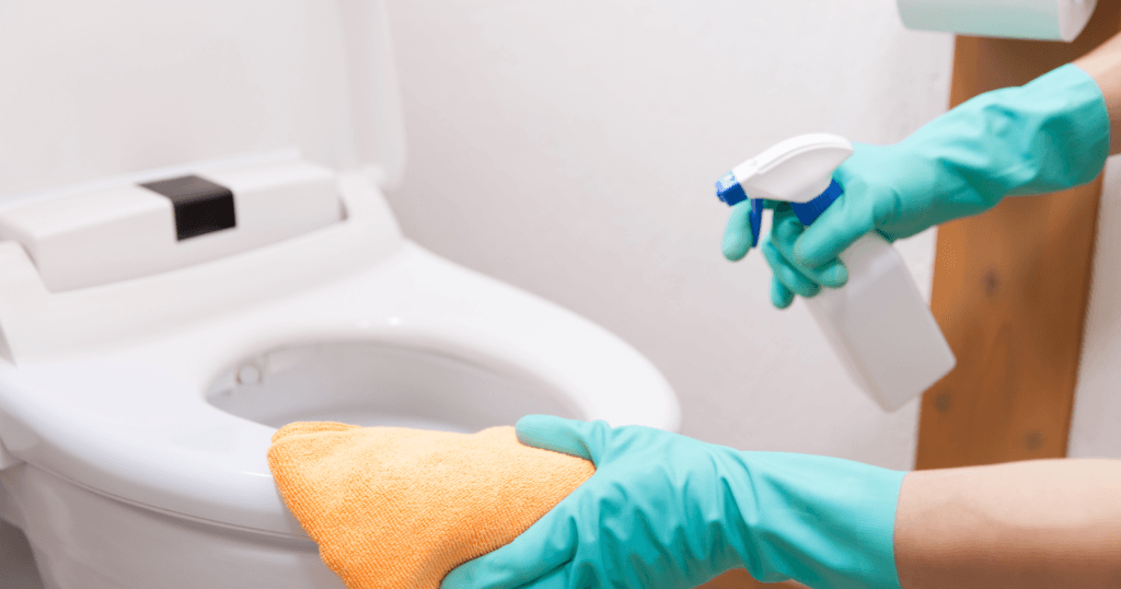 The Best Toilet Seat Surface for Cleaning- hands cleaning a toilet seat