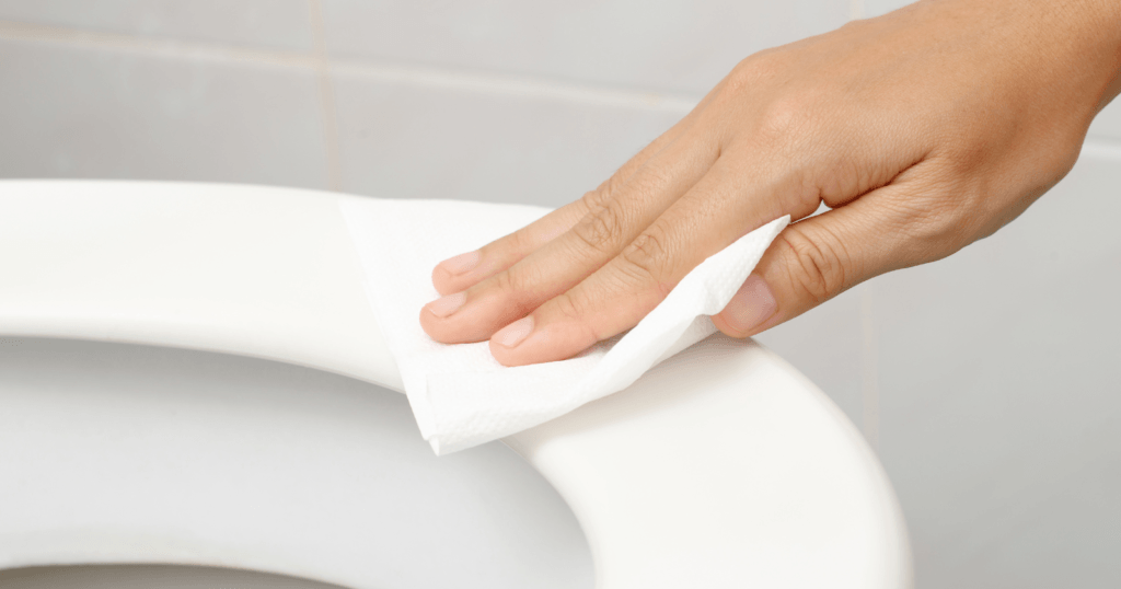 The Best Toilet Seat Surface for Cleaning- hands cleaning a toilet seat